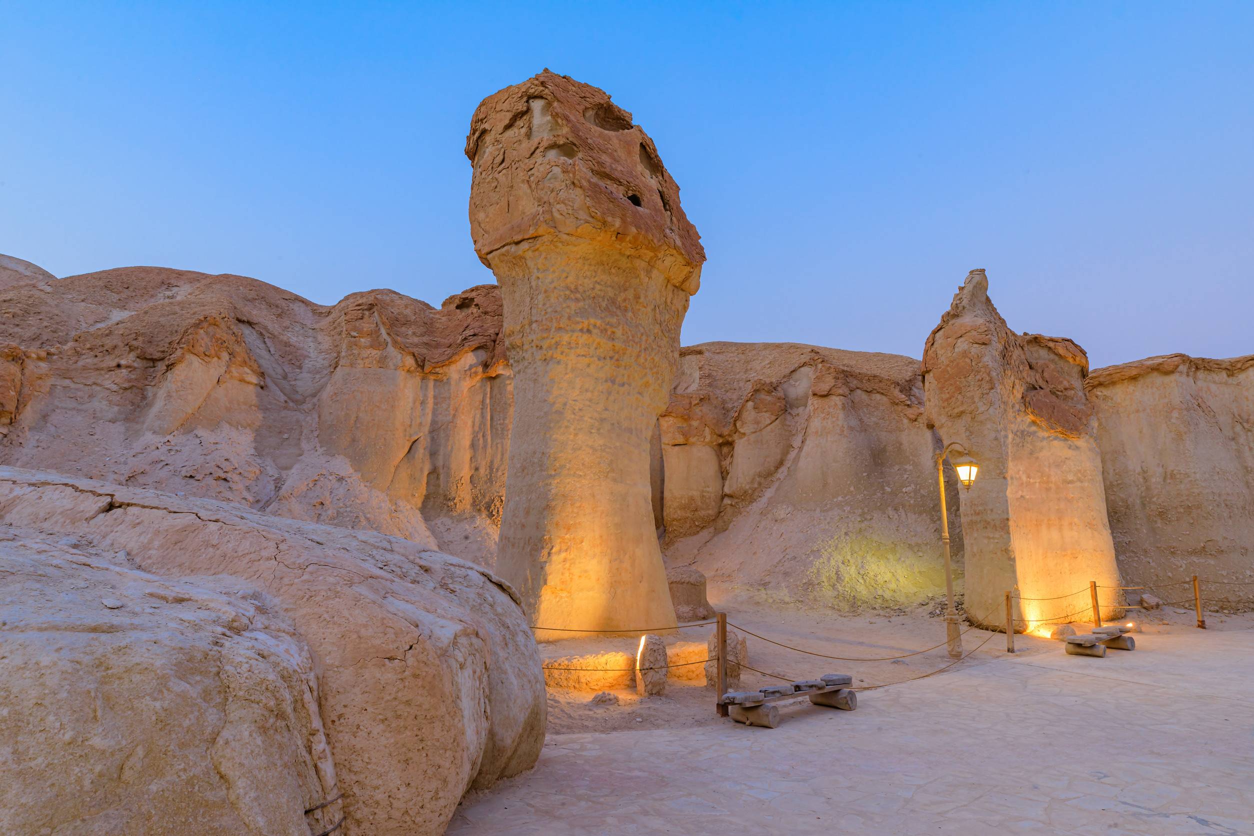 Soft Evening Light Illuminating Sandstone Formations And Walking Path Inside Jabal Al Qarah Mountain