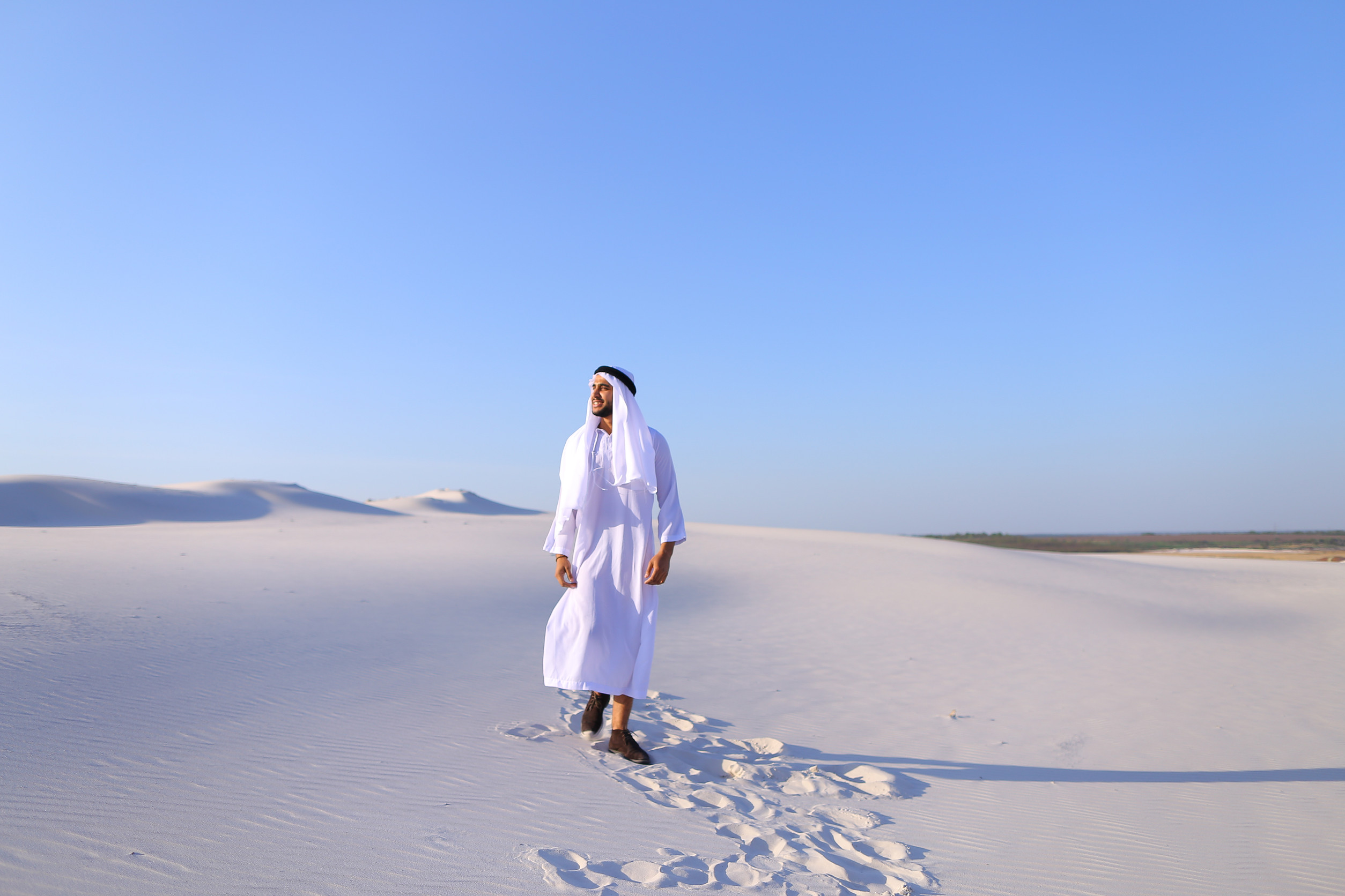 Stately Young Sheikh Walks On Foot Along Bottomless Desert Leaving Traces On Sand Enjoying Warm